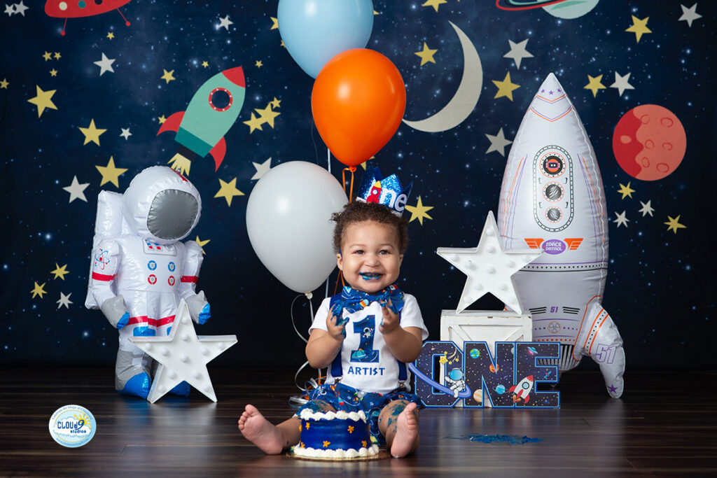 baby boy smashing his first birthday cake in a space inspired themed set at Cloud 9 Studios