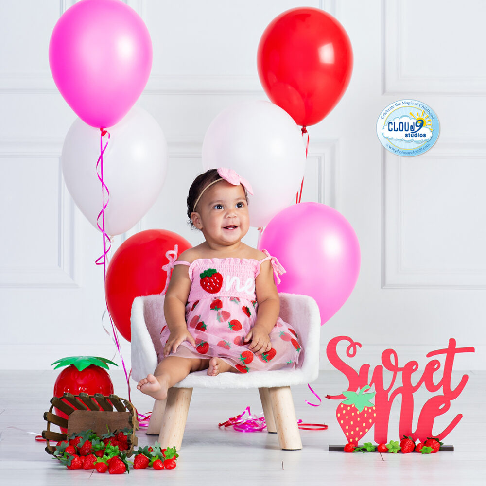 baby girl in a first birthday setting that is a Sweet One strawberry theme at Cloud 9 Studios