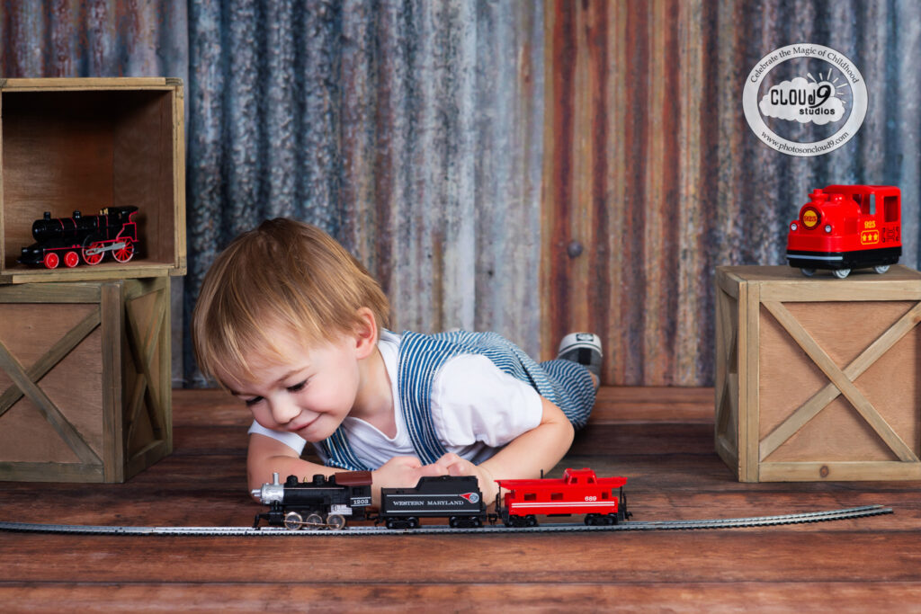 a 2 year old boy playing with trains during a photo session at Cloud 9 Studios in Wesley Chapel, Florida
