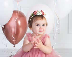 close up of baby girl with her birthday balloons clapping while celebrating her first birthday in Wesley Chapel just north of Tampa, Florida
