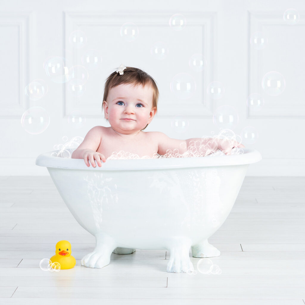 Baby splashing in bubble bath finale during first birthday photoshoot.