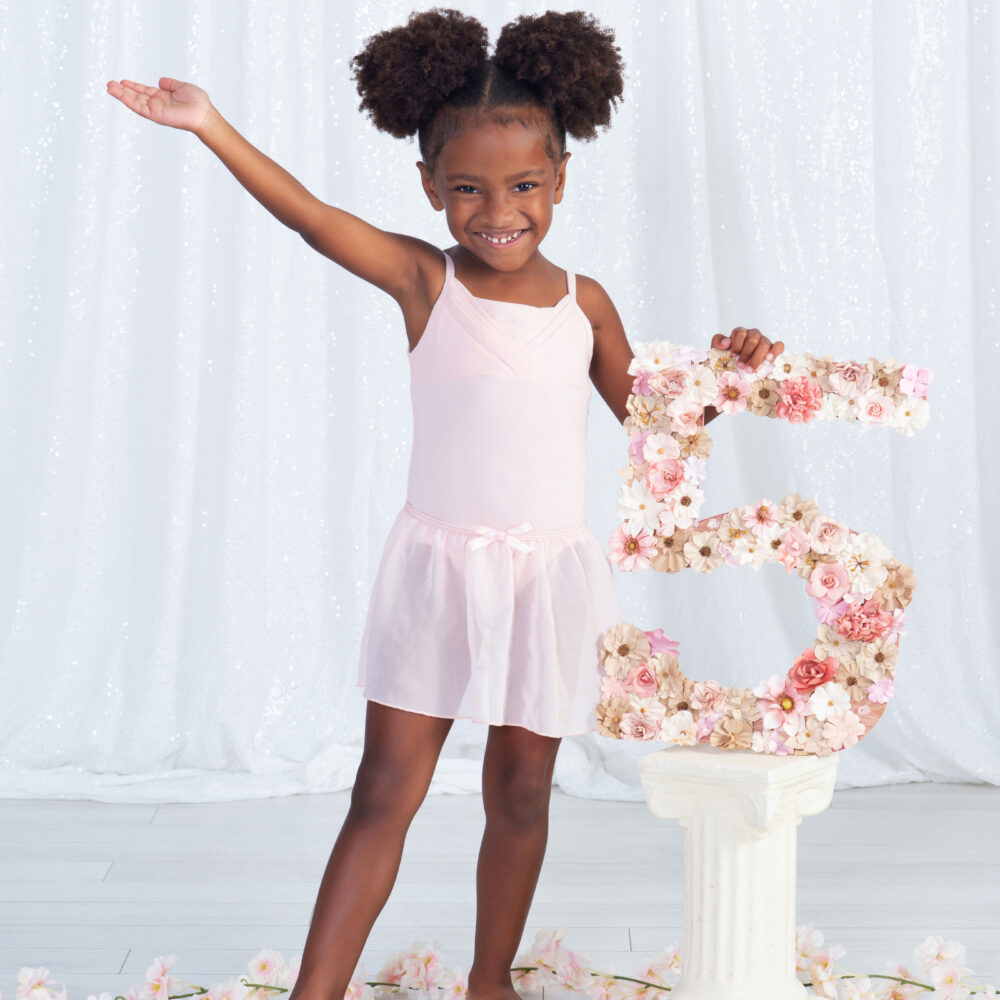 a five year old girl saying "ta da" as she proudly holds her number 5 in a ballet pose at Cloud 9 Studios in Wesley Chapel, Florida