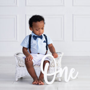 baby boy looking down as he holds the word ONE to celebrate his first birthday at Cloud 9 Studios in Wesley Chapel, Florida just north of Tampa