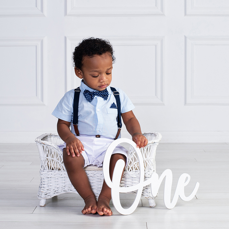 baby boy looking down as he holds the word ONE to celebrate his first birthday at Cloud 9 Studios in Wesley Chapel, Florida just north of Tampa