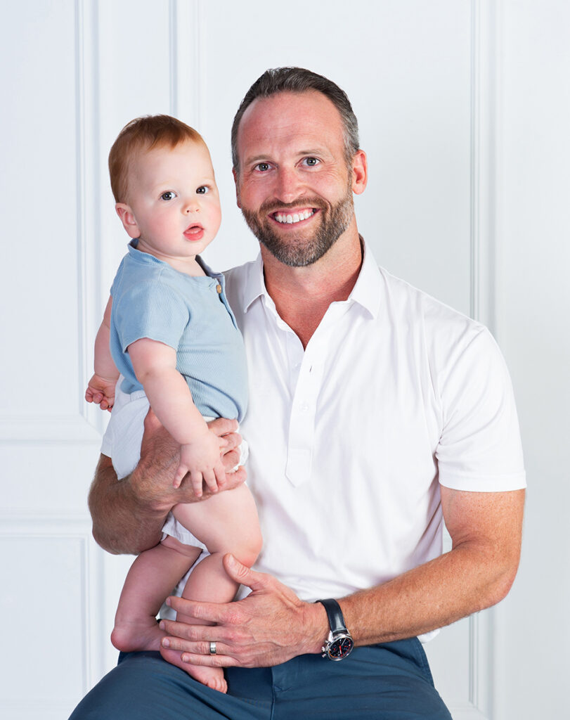 A dad smiling excited to be snuggled up with his one year old son at Cloud 9 Studios in Wesley Chapel, Florida
