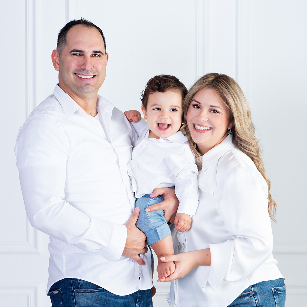 a mom tickling the feet of her one year old son as he laughs in her and her husband's arms, celebrating his first birthday at Cloud 9 Studios in Wesley Chapel, Florida