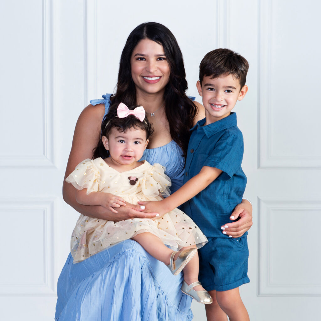 a mom smiling and happy as she snuggles both of her kids while celebrating her daughter's first birthday at Cloud 9 Studios in Wesley Chapel, Florida