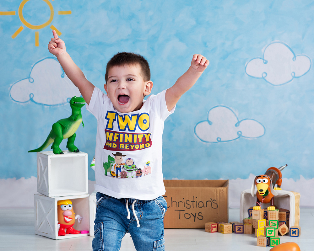 A two year old boy running with excitement with hands over his head as he has fun taking his birthday portraits at Cloud 9 Studios in Wesley Chapel, Florida