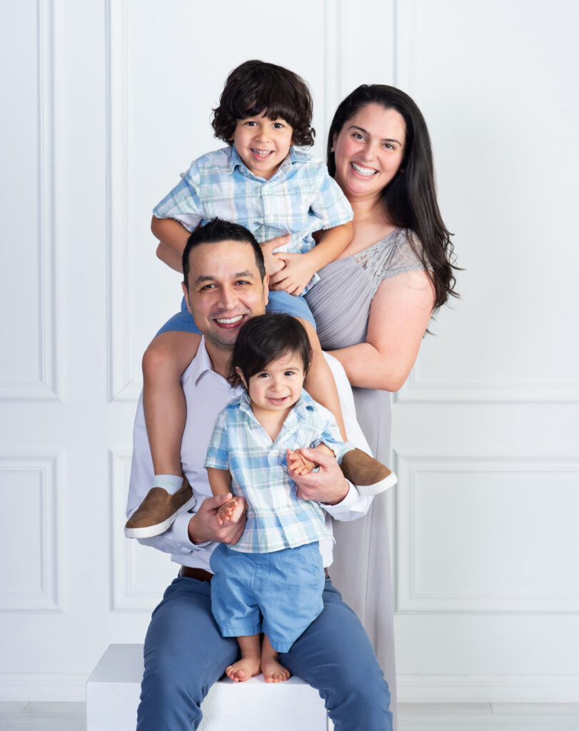 Family of four playing together at Cloud 9 Studios for a portrait in light shades of blue and grey,