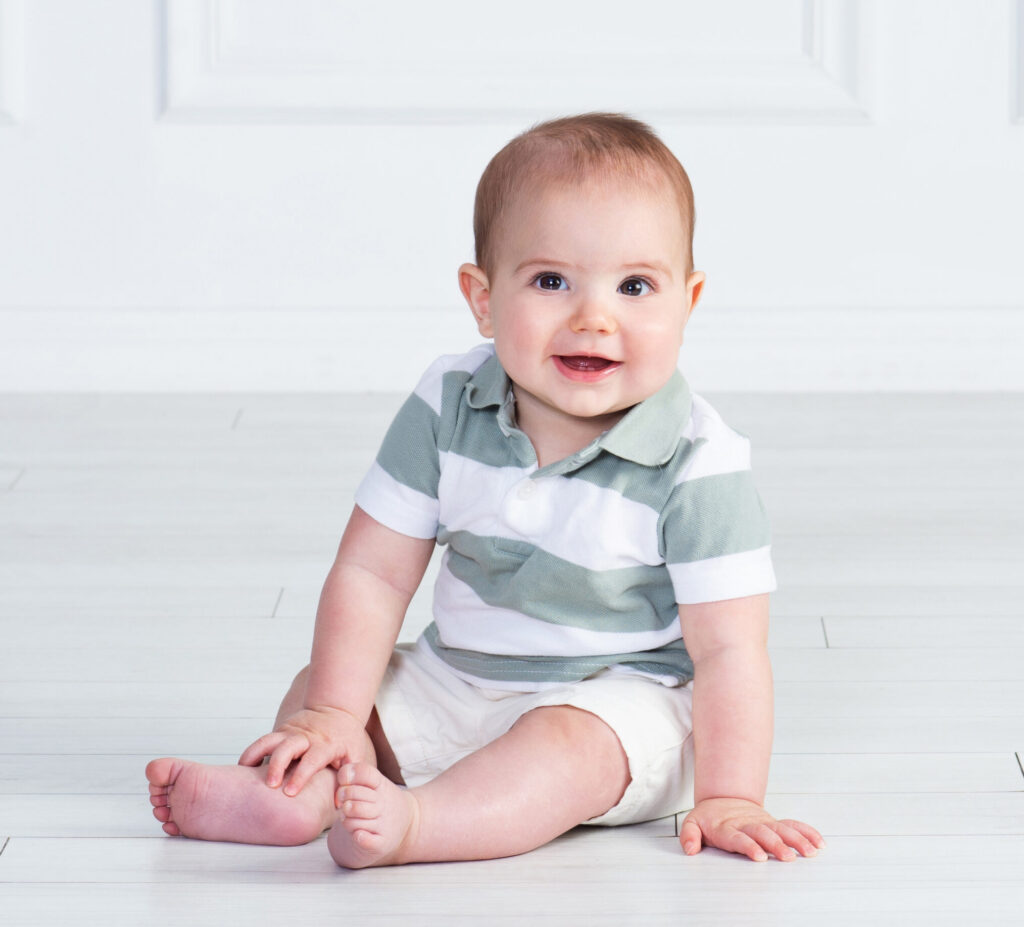 baby boy sitting up at 6 months old with a smile at Cloud 9 Studios in Wesely Chapel, Florida