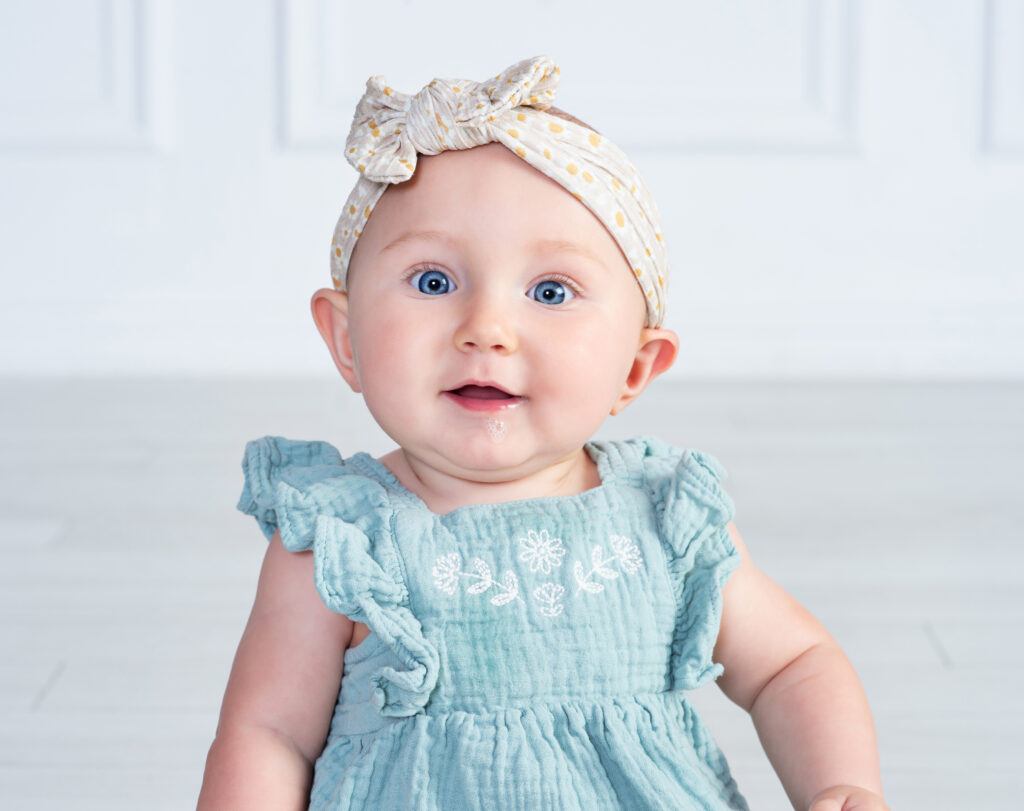 Baby girl with big wide eyes blowing bubbles with a smile during her 6 month session at Cloud 9 Studios in Wesley Chapel, Florida