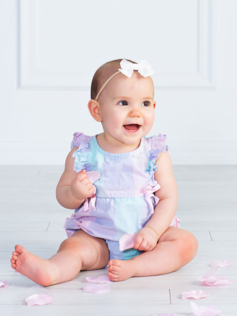 baby girl sitting up at 6 months with a big smile at Cloud 9 Studios in Wesley Chapel, Florida