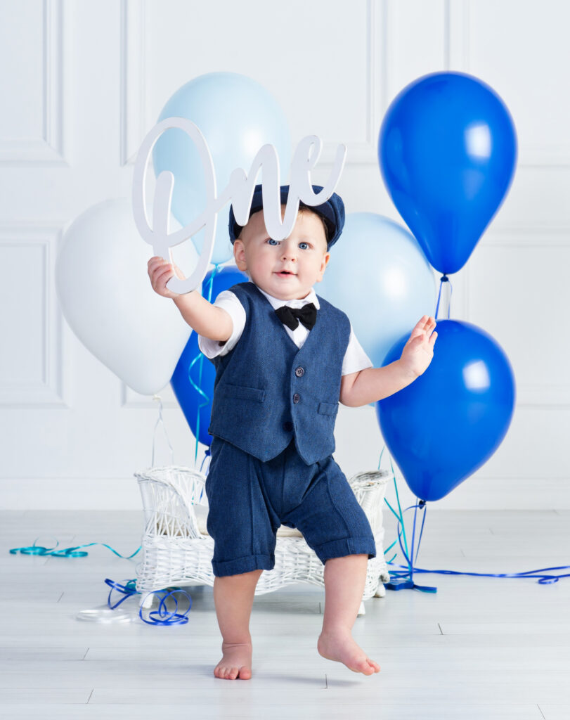 Baby boy running away from his balloons at a first birthday portrait session in Wesley Chapel, Florida