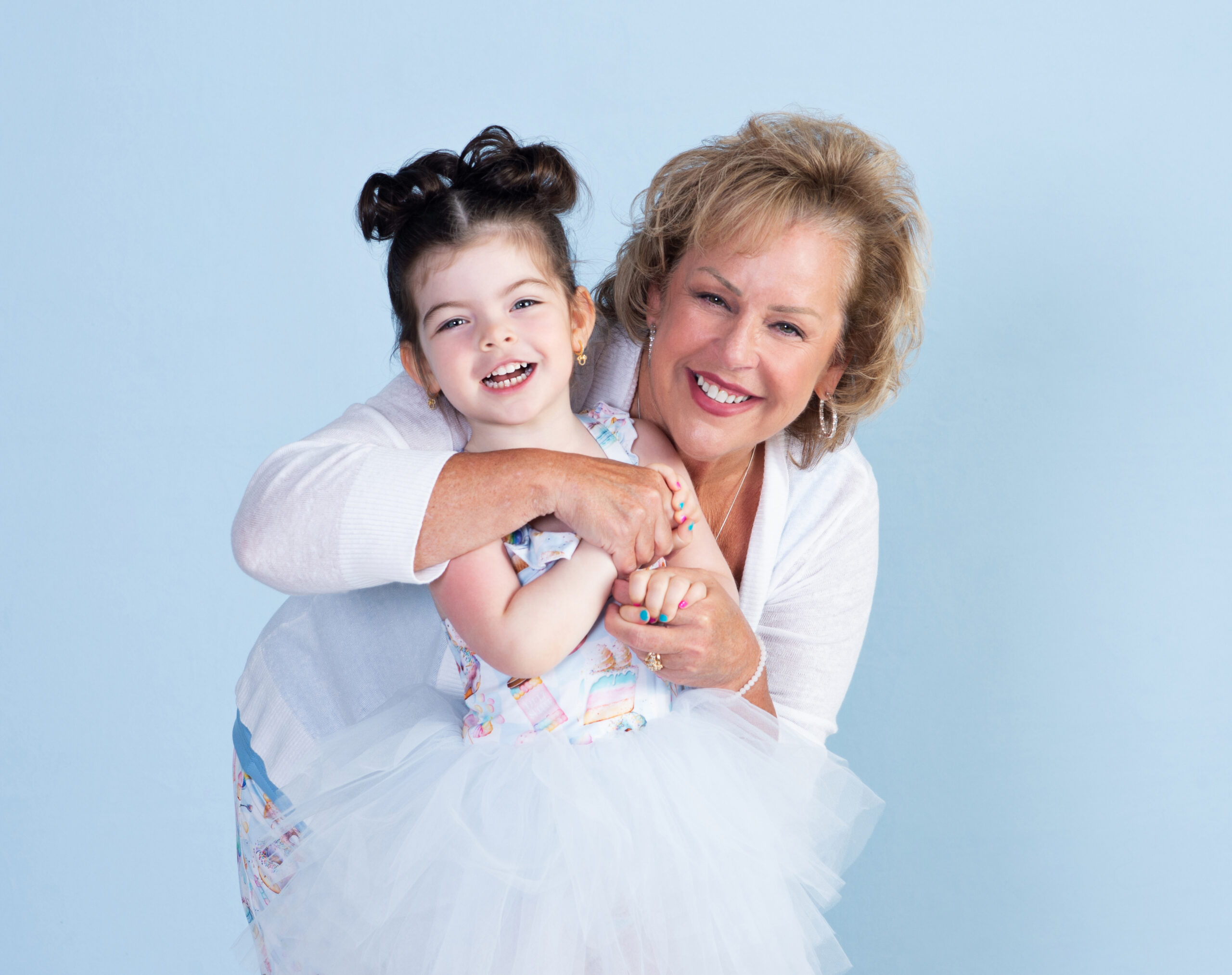 Grandmother hugging and laughing with her granddaughter during a Grandparent and Me portrait session