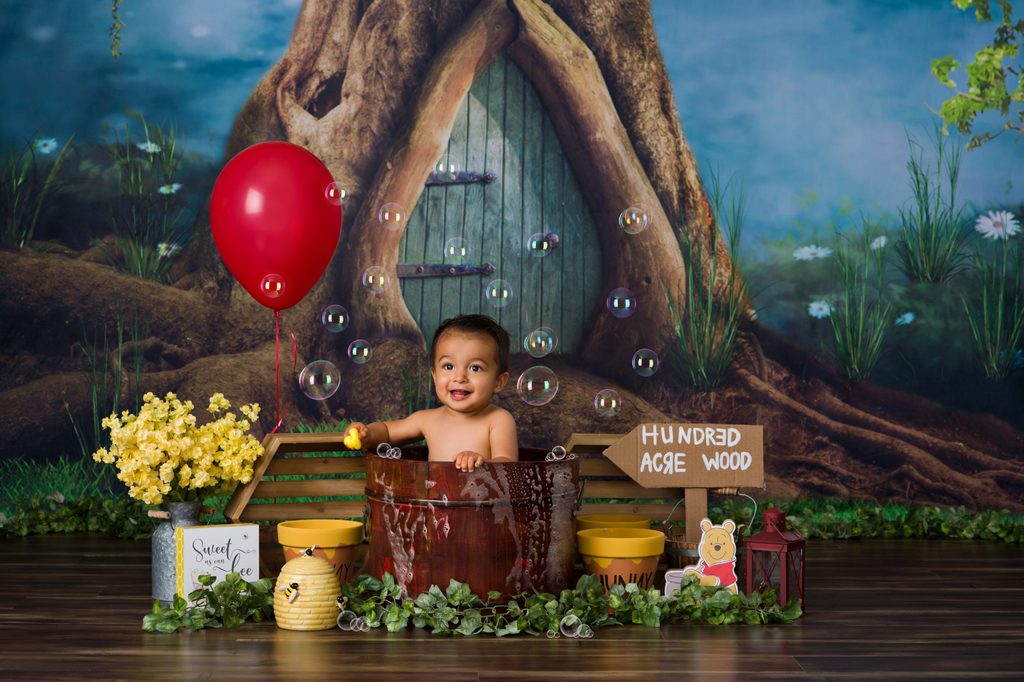 Smiling baby boy laughing during his Winnie the Pooh-themed first birthday portraits.